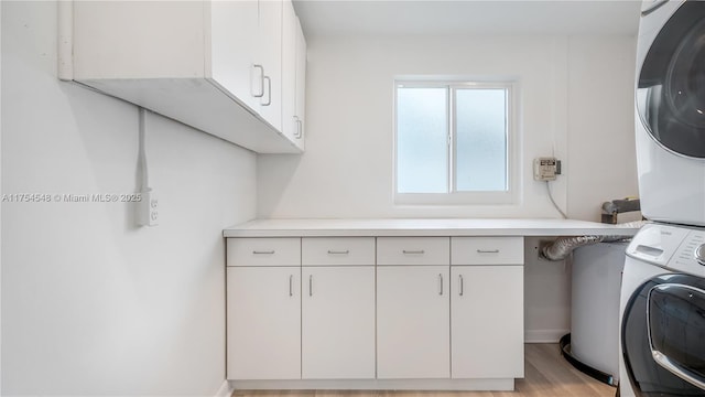 washroom with stacked washing maching and dryer, light wood-style flooring, and cabinet space