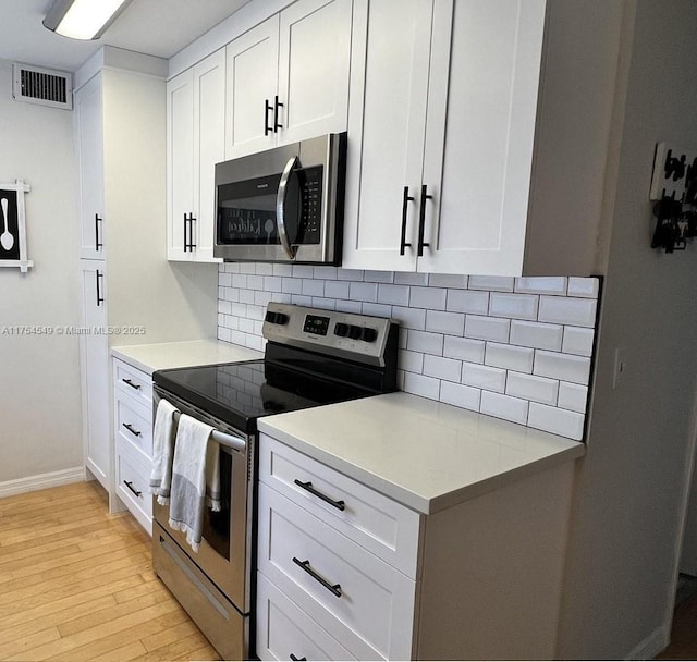 kitchen with light countertops, appliances with stainless steel finishes, visible vents, and decorative backsplash