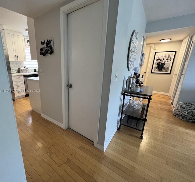 corridor featuring a toaster, light wood-type flooring, and baseboards