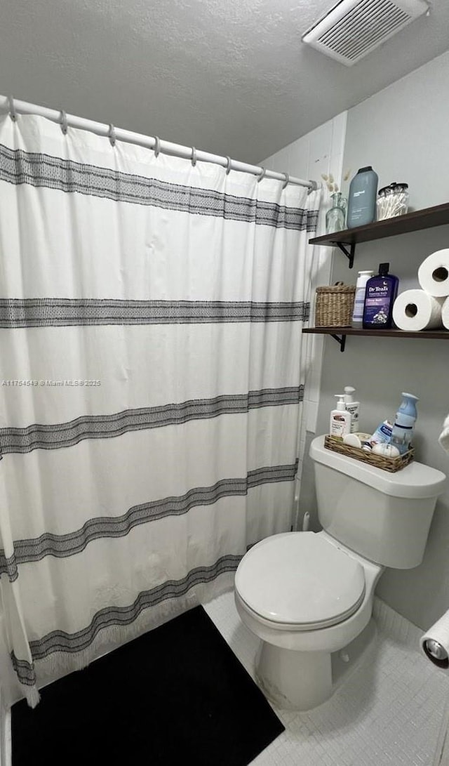 bathroom featuring visible vents, a shower with shower curtain, toilet, tile patterned flooring, and a textured ceiling