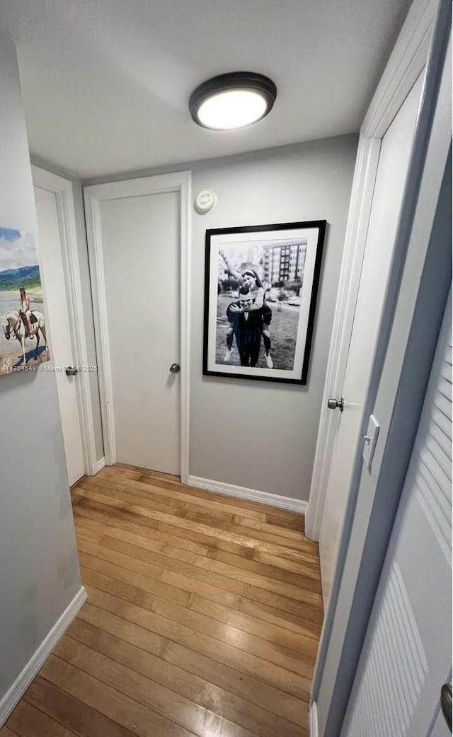 corridor featuring light wood finished floors and baseboards