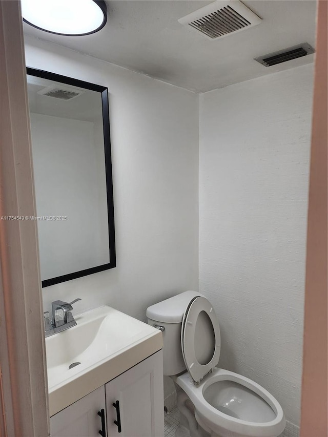 half bathroom with toilet, visible vents, and vanity