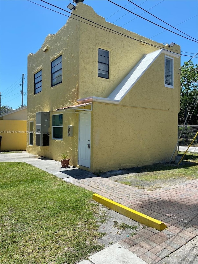 view of front facade with a front yard, stucco siding, and fence