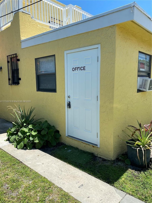 entrance to property featuring cooling unit and stucco siding