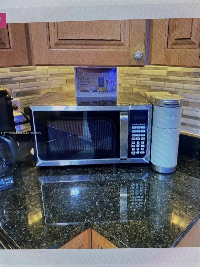 interior details featuring stainless steel microwave and dark stone countertops