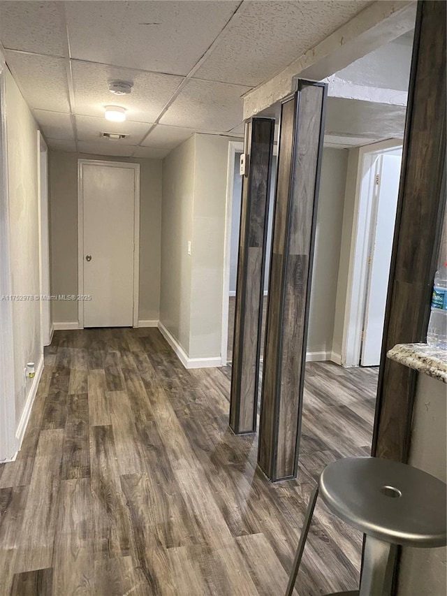 corridor with visible vents, baseboards, wood finished floors, and a drop ceiling