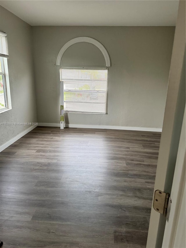 empty room featuring dark wood-type flooring and baseboards