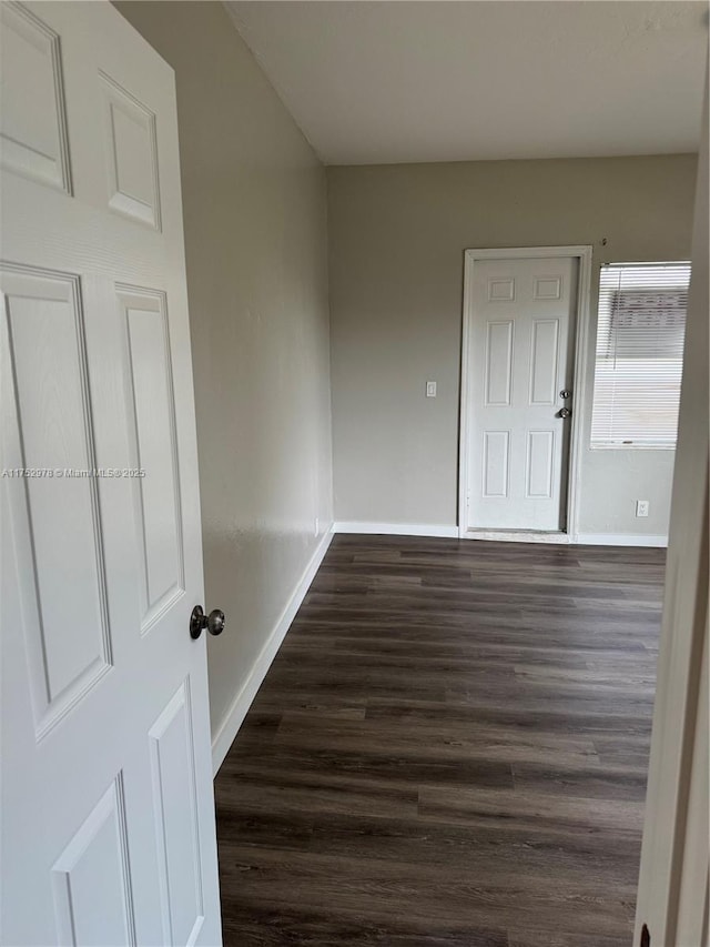 unfurnished room with dark wood-type flooring and baseboards
