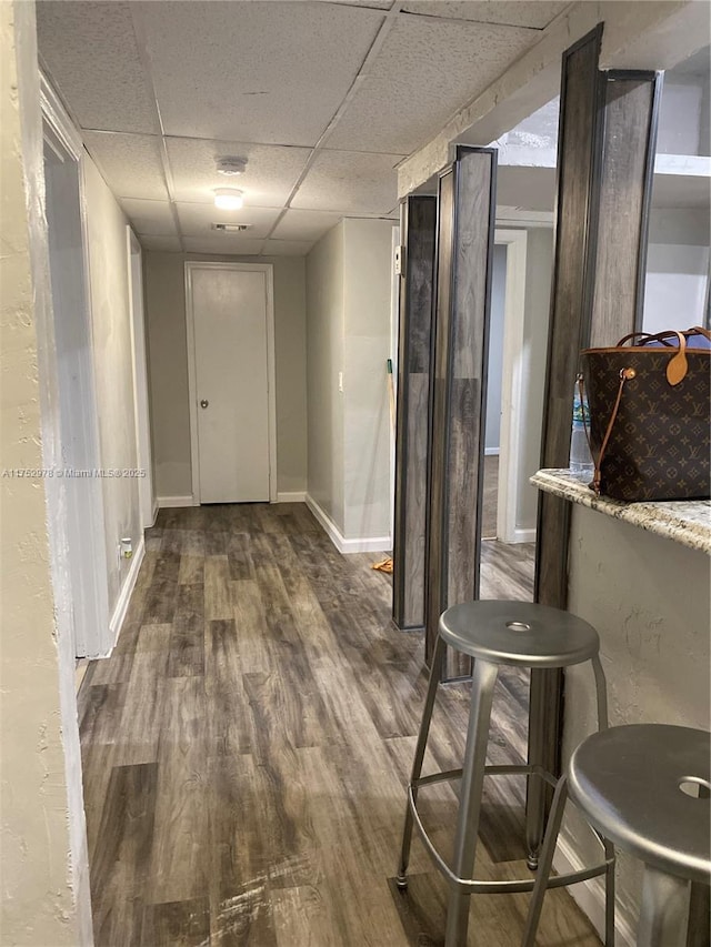 corridor with baseboards, a drop ceiling, and wood finished floors