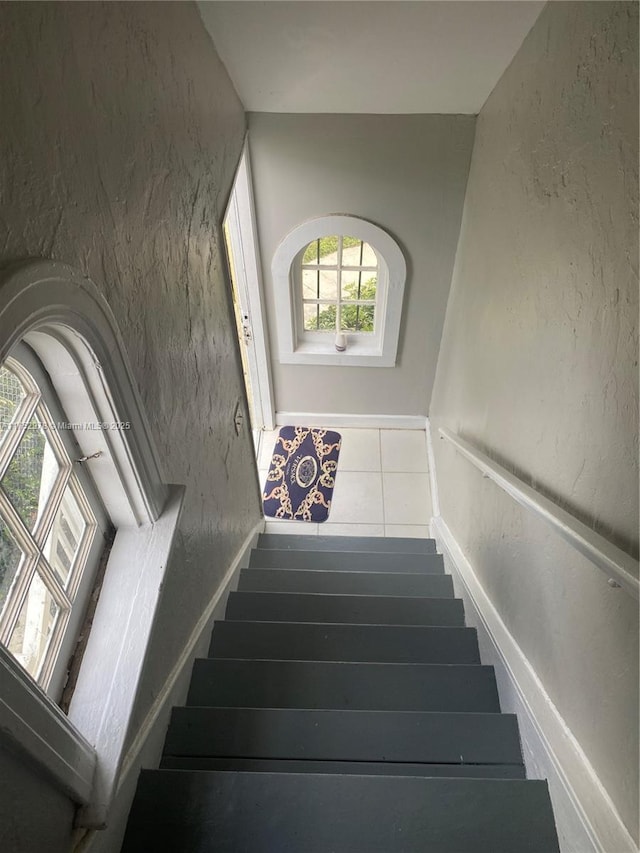 staircase with a textured wall and baseboards