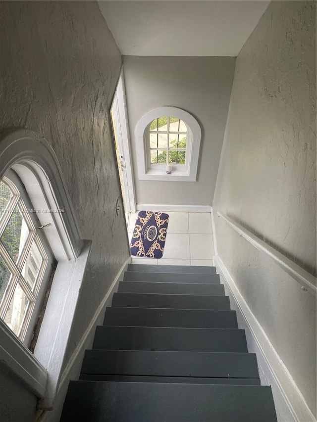 stairway featuring a textured wall and tile patterned flooring