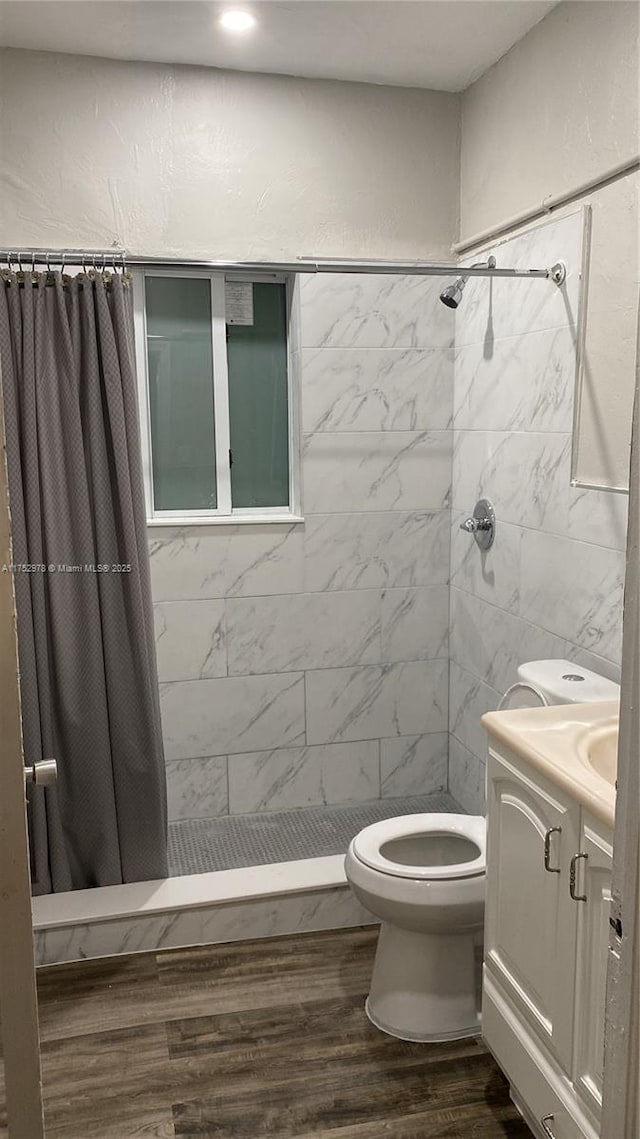 bathroom featuring vanity, a stall shower, wood finished floors, and toilet