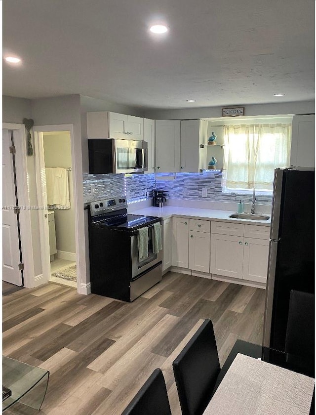 kitchen featuring decorative backsplash, dark wood-style floors, appliances with stainless steel finishes, light countertops, and a sink