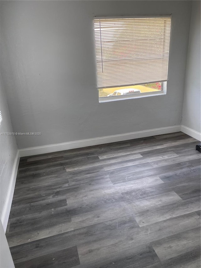 spare room featuring baseboards and wood finished floors