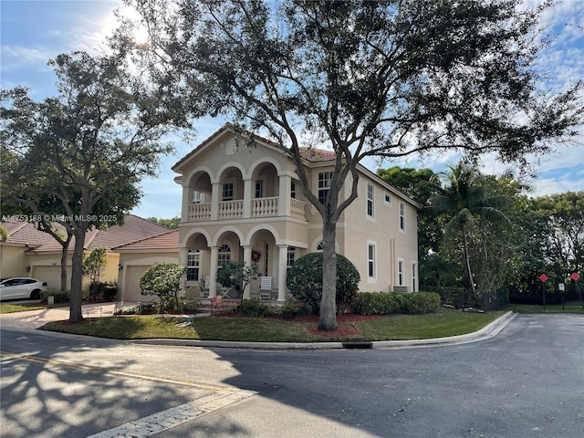 mediterranean / spanish-style house featuring stucco siding, a balcony, a garage, driveway, and a tiled roof