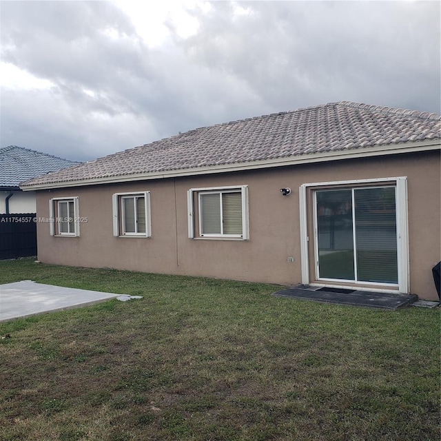 back of property featuring a lawn, a patio area, and stucco siding