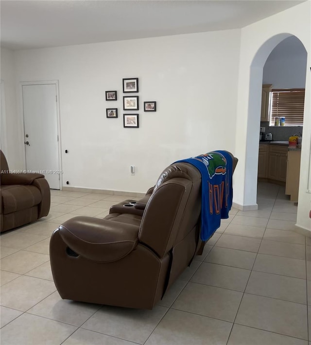 living area with light tile patterned floors, arched walkways, and baseboards