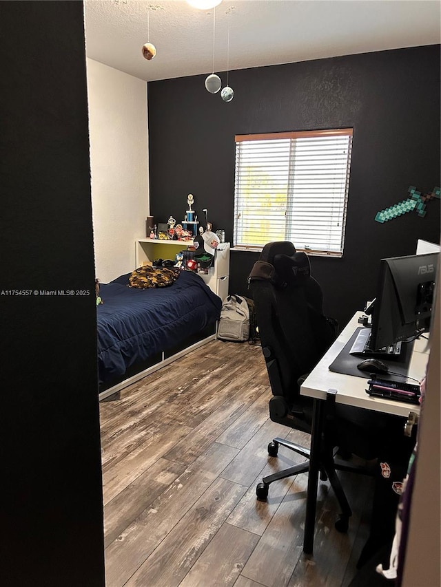 bedroom with a textured ceiling and wood finished floors