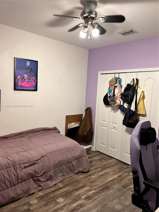 bedroom featuring dark wood-type flooring, a closet, visible vents, and ceiling fan