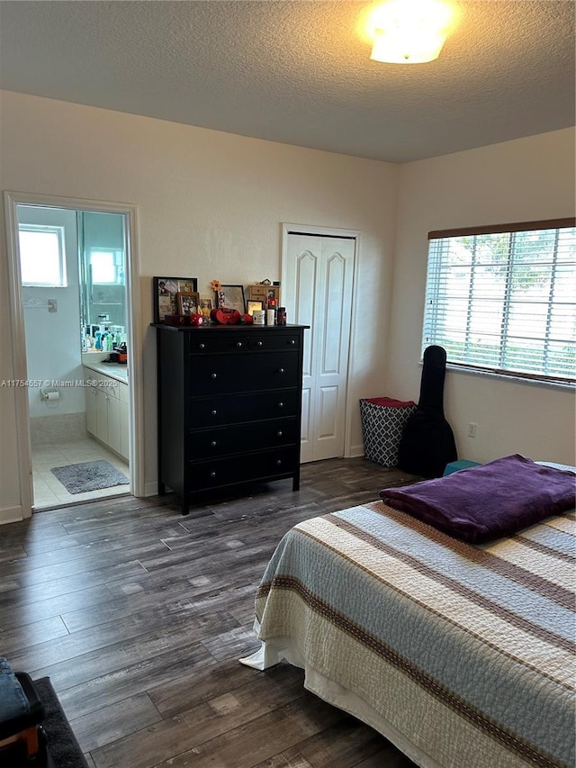 bedroom featuring multiple windows, dark wood finished floors, and a textured ceiling