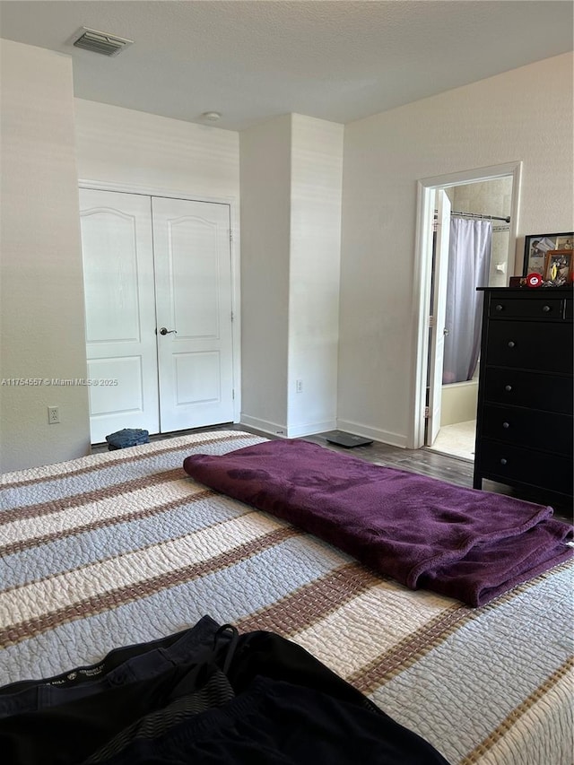 bedroom with a closet, visible vents, baseboards, and ensuite bathroom