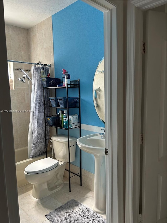 full bath with a sink, shower / tub combo with curtain, toilet, and tile patterned floors