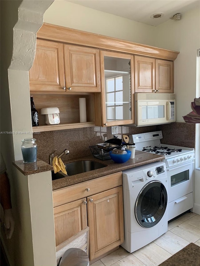 kitchen with white microwave, a sink, dark stone counters, washer / clothes dryer, and range with gas cooktop