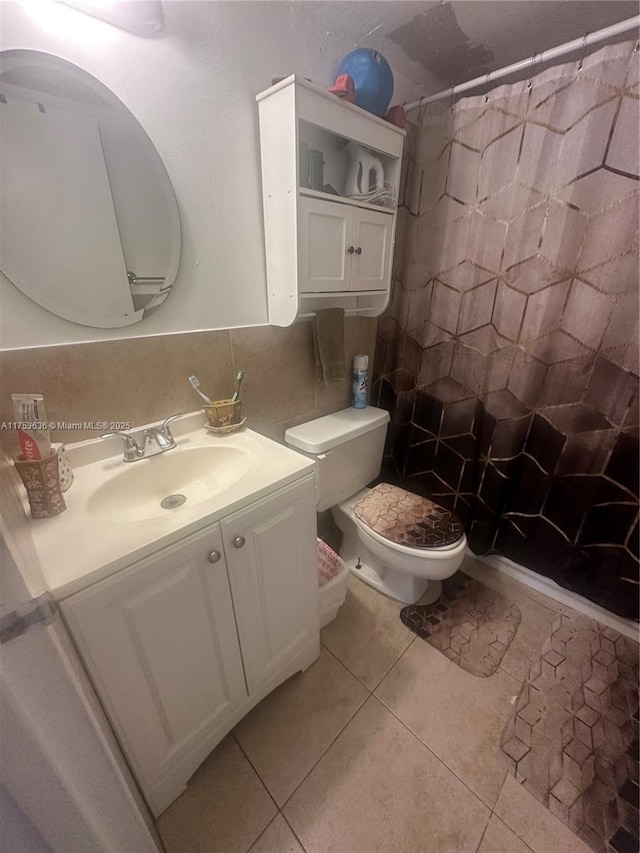 bathroom featuring toilet, a shower with curtain, tile patterned flooring, vanity, and tile walls