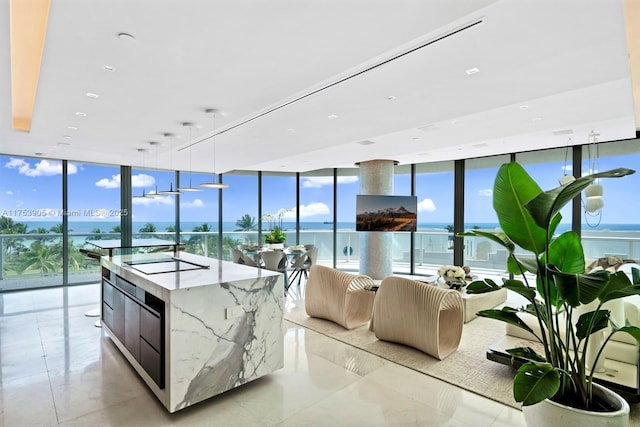 kitchen with pendant lighting, black electric stovetop, light stone countertops, modern cabinets, and a wall of windows