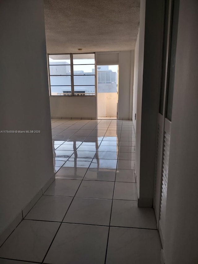 corridor featuring a textured ceiling and tile patterned floors