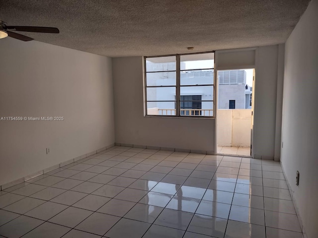 empty room with ceiling fan, a textured ceiling, baseboards, and light tile patterned floors