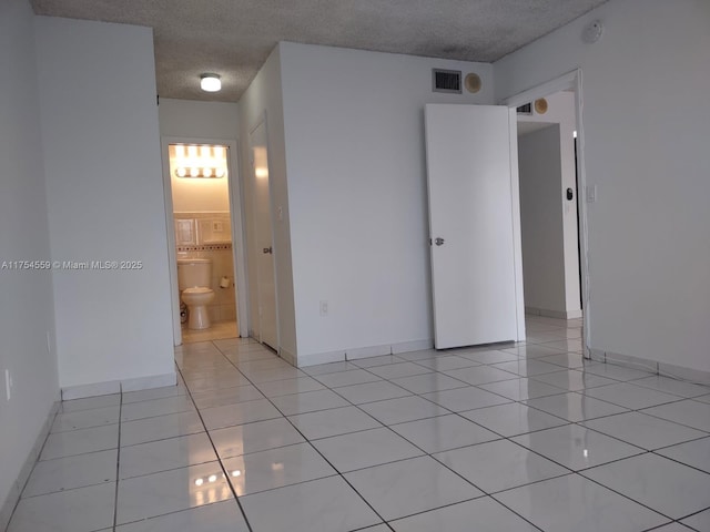 unfurnished room with visible vents, a textured ceiling, baseboards, and light tile patterned floors