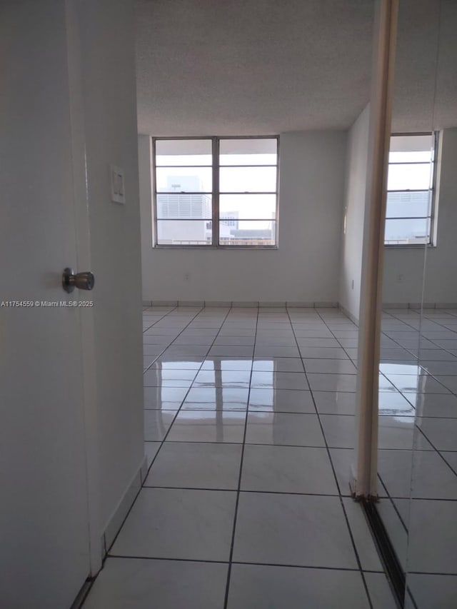 unfurnished room featuring a healthy amount of sunlight, a textured ceiling, and light tile patterned floors