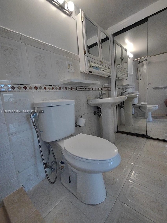 full bathroom featuring a shower, tile patterned flooring, toilet, and tile walls