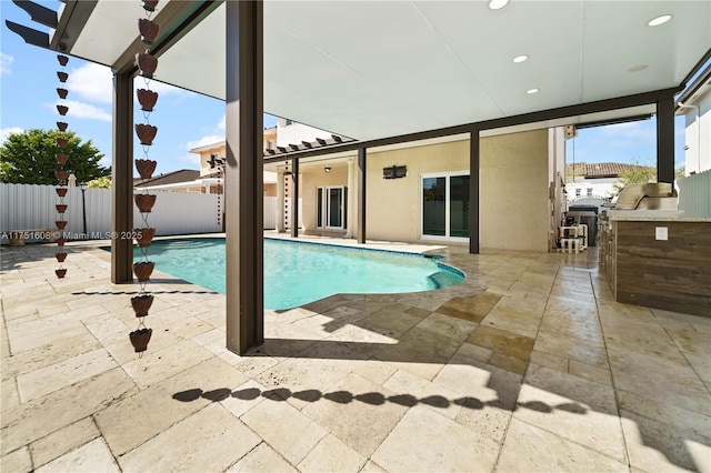 view of swimming pool featuring a fenced in pool, a patio, an outdoor kitchen, and a fenced backyard