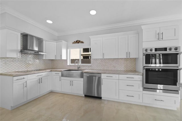 kitchen with a sink, stainless steel appliances, wall chimney exhaust hood, white cabinets, and crown molding