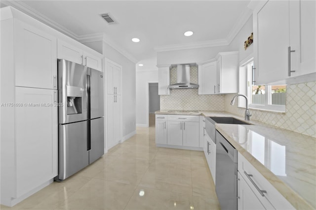 kitchen featuring light stone counters, stainless steel appliances, a sink, white cabinetry, and wall chimney exhaust hood