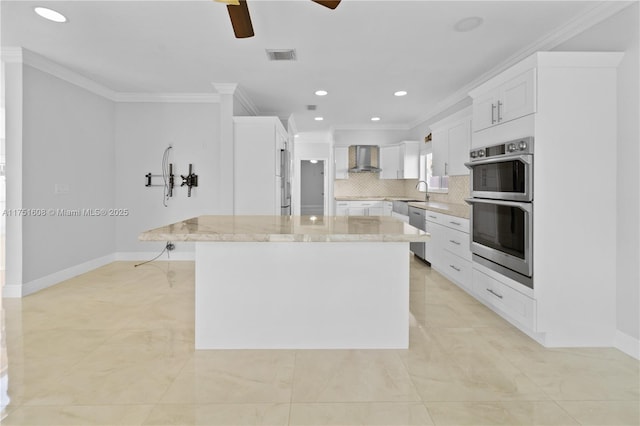 kitchen with crown molding, wall chimney exhaust hood, a ceiling fan, and appliances with stainless steel finishes