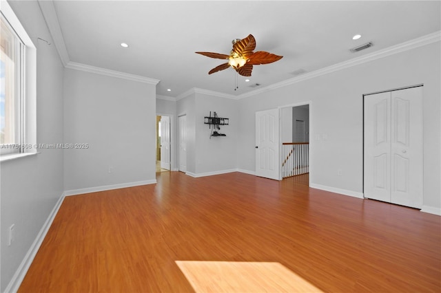 unfurnished living room with ceiling fan, wood finished floors, visible vents, baseboards, and crown molding