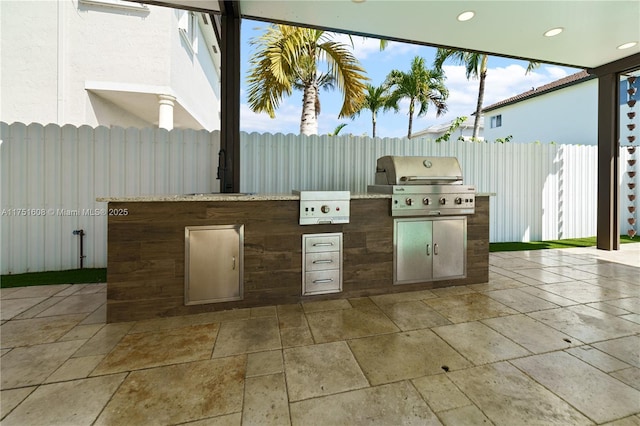 view of patio / terrace featuring fence, exterior kitchen, and area for grilling