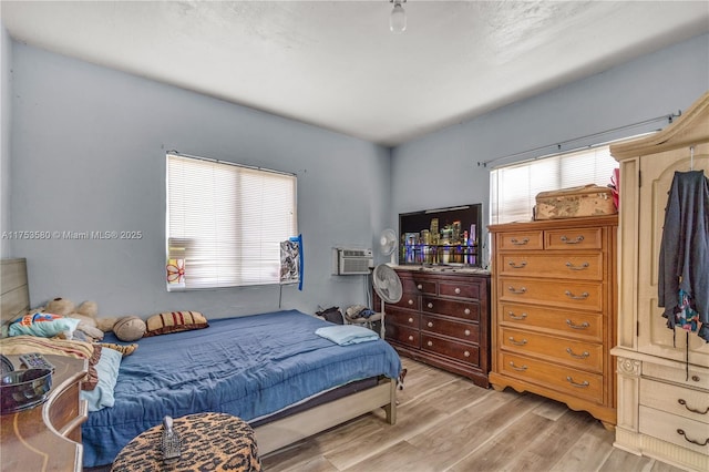 bedroom featuring light wood-style floors and a wall mounted AC