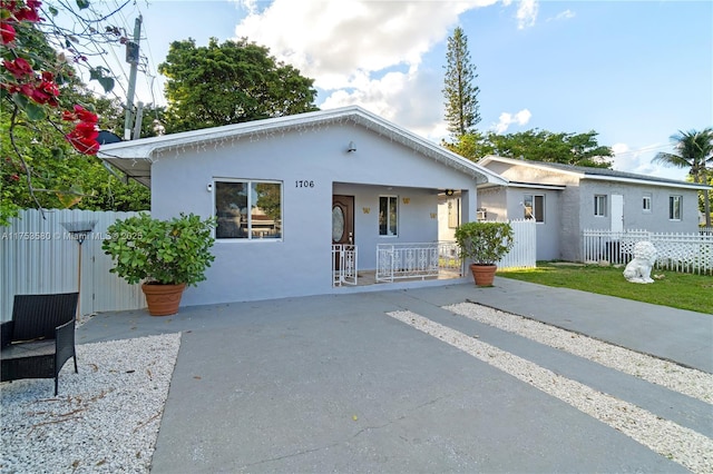 view of front of home with covered porch, fence, and stucco siding