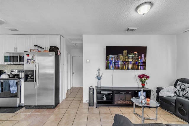 living area with light tile patterned flooring, visible vents, and a textured ceiling