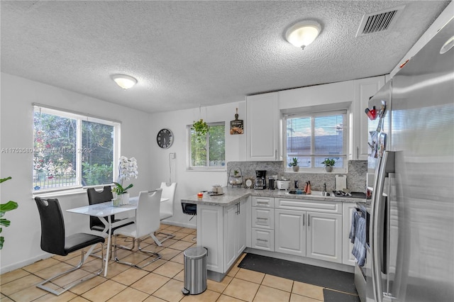 kitchen featuring visible vents, decorative backsplash, white cabinetry, stainless steel refrigerator with ice dispenser, and light tile patterned flooring