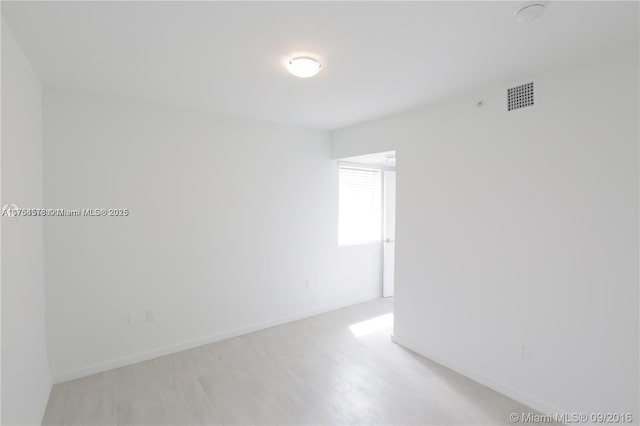 unfurnished room featuring light wood-style floors, baseboards, and visible vents