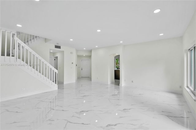 spare room with arched walkways, recessed lighting, visible vents, marble finish floor, and stairway