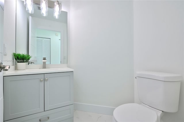 half bath featuring marble finish floor, vanity, toilet, and baseboards