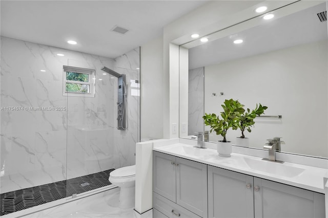 bathroom with double vanity, a marble finish shower, toilet, marble finish floor, and a sink