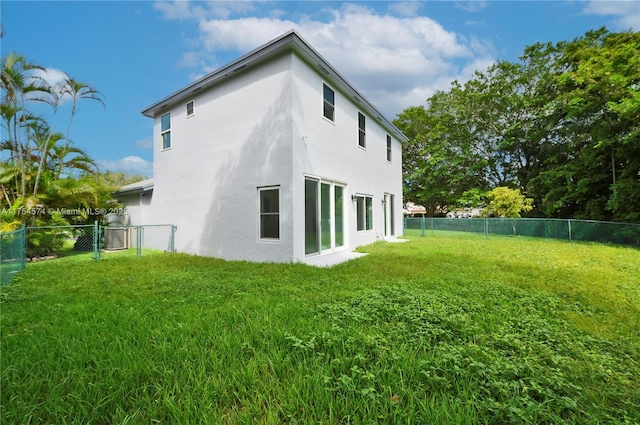 back of property with a fenced backyard, a yard, and stucco siding