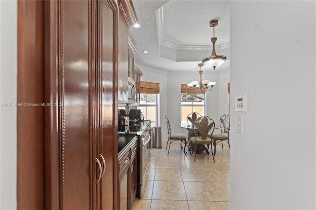 kitchen with crown molding, light tile patterned floors, stainless steel appliances, a raised ceiling, and a textured ceiling